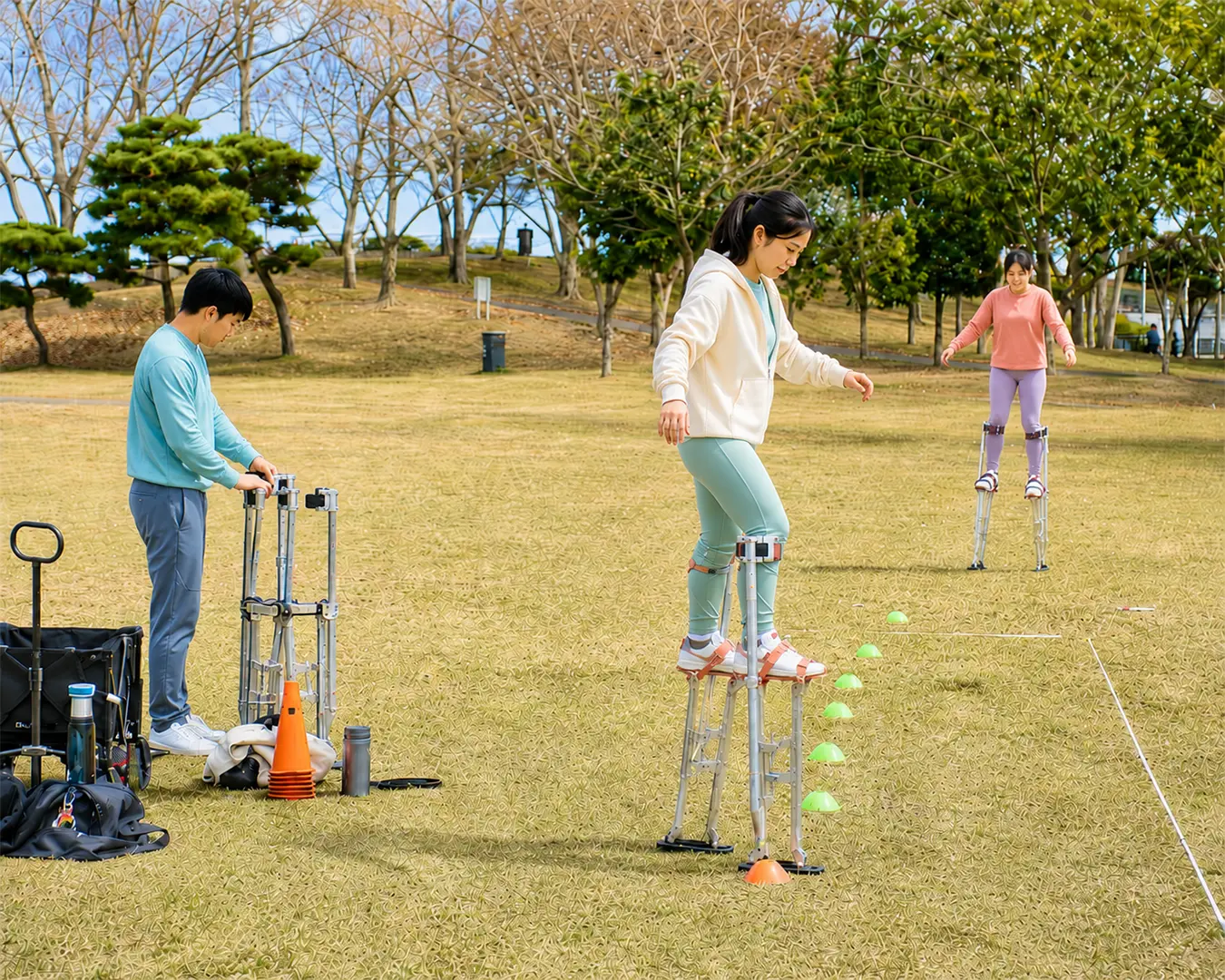 公園で複数人がスティルトの歩行練習を行い、コーンを使ってトレーニングしている様子
